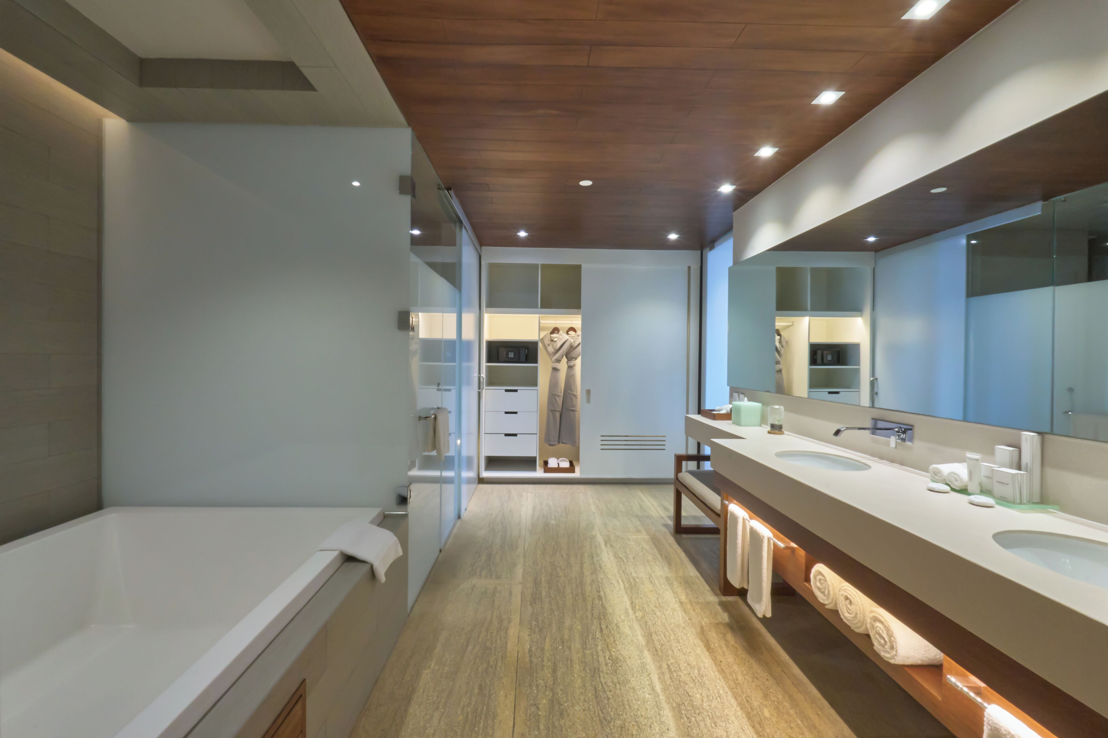 A modern bathroom with a large bathtub, dual sinks, and a walk-in shower.
