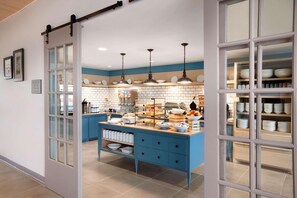 A kitchen with a blue island, white cabinets, and hanging pendant lights. - Country Inn & Suites by Radisson, Enid, OK (Enid)