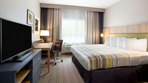 A hotel room with a bed, a desk with a chair, a television, and a window with curtains. - Country Inn & Suites by Radisson, Enid, OK (Enid)