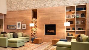 A modern living room with a fireplace, green sofas, wooden side tables, and a bookshelf. - Country Inn & Suites by Radisson, Enid, OK (Enid)