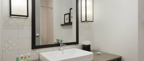 Une salle de bain avec un lavabo blanc, un grand miroir et un porte-serviettes.