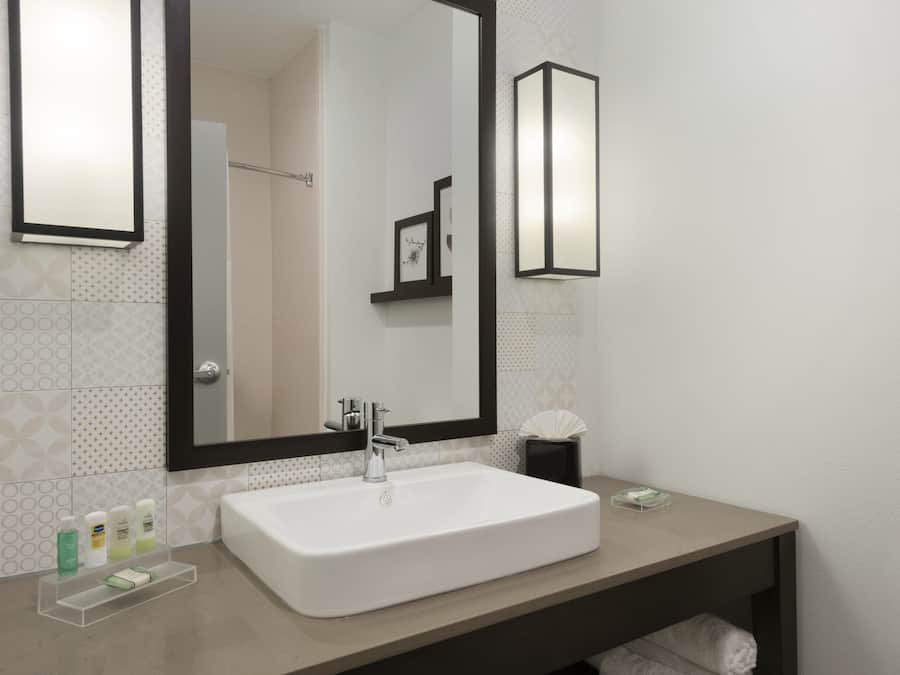 A bathroom with a white sink, a large mirror, and a towel rack.