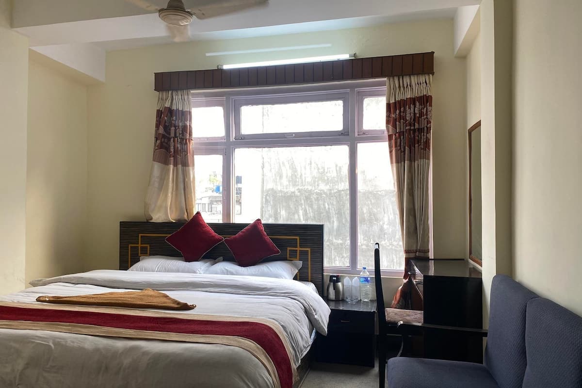 Ein Hotelzimmer mit Bett, Stuhl, Schreibtisch und einem Vorhangfenster.