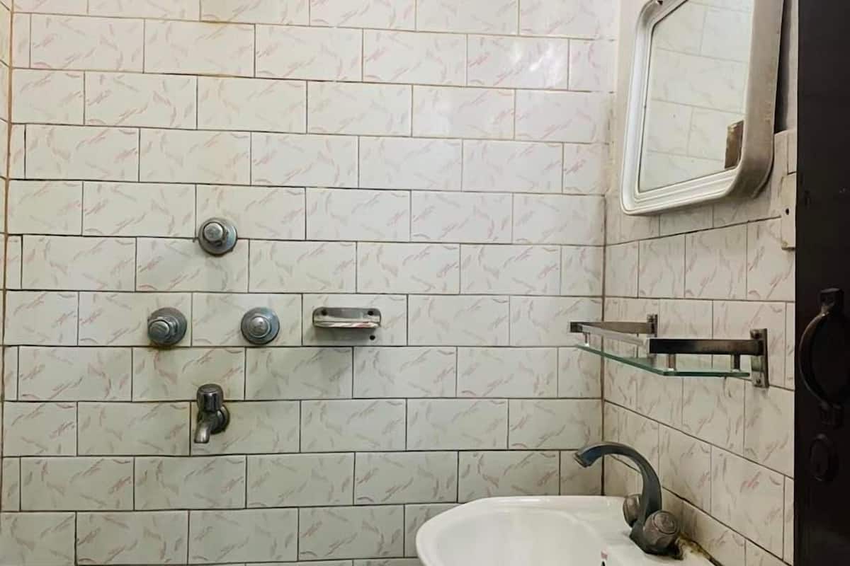 Ein Badezimmer mit einem weißen Waschbecken, einem Spiegel und einer Dusche mit Duschbrause.