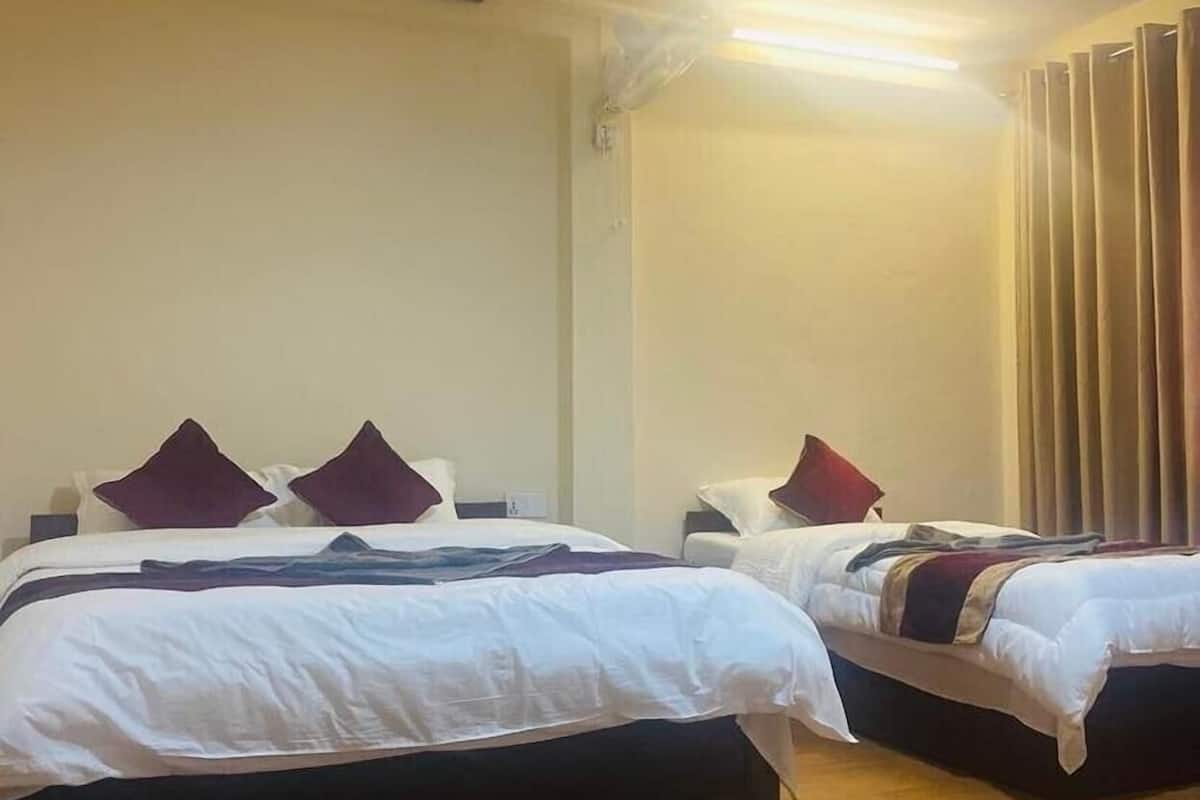 Ein Hotelzimmer mit zwei Betten, Holzboden und einer Deckenleuchte.