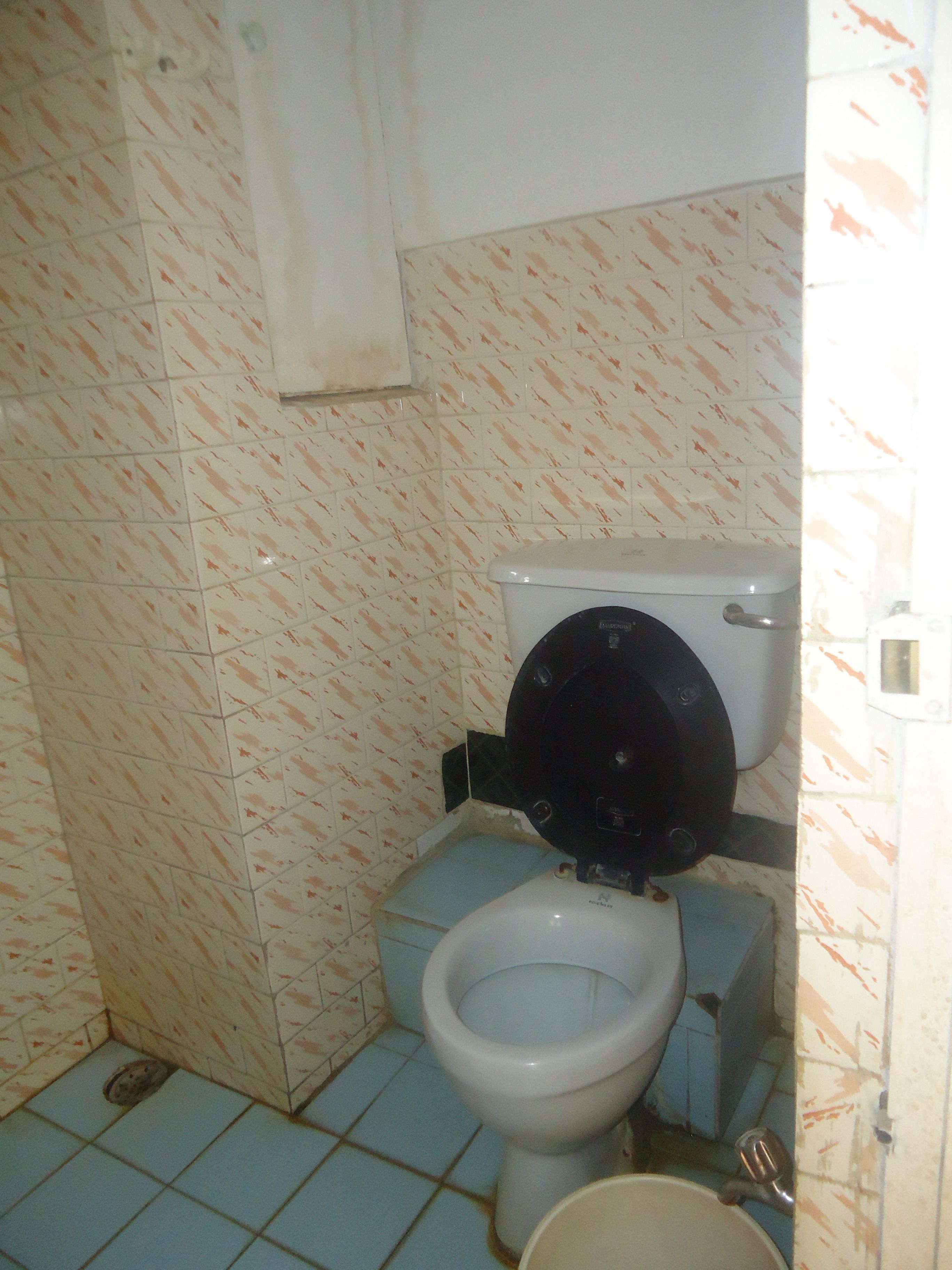 A small bathroom with a toilet, a sink, and a tiled floor.