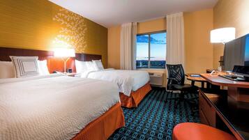 A hotel room with two beds, a desk, a chair, and a TV.