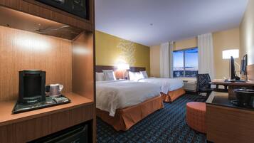A hotel room with a bed, a desk, a coffee maker, and a view of the cityscape.