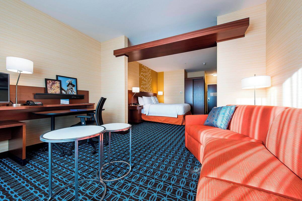 A hotel room with a bed, a sofa, a desk, and a chair.