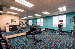 Un gimnasio con equipo de ejercicio, dispensador de agua y un amplio ventanal.