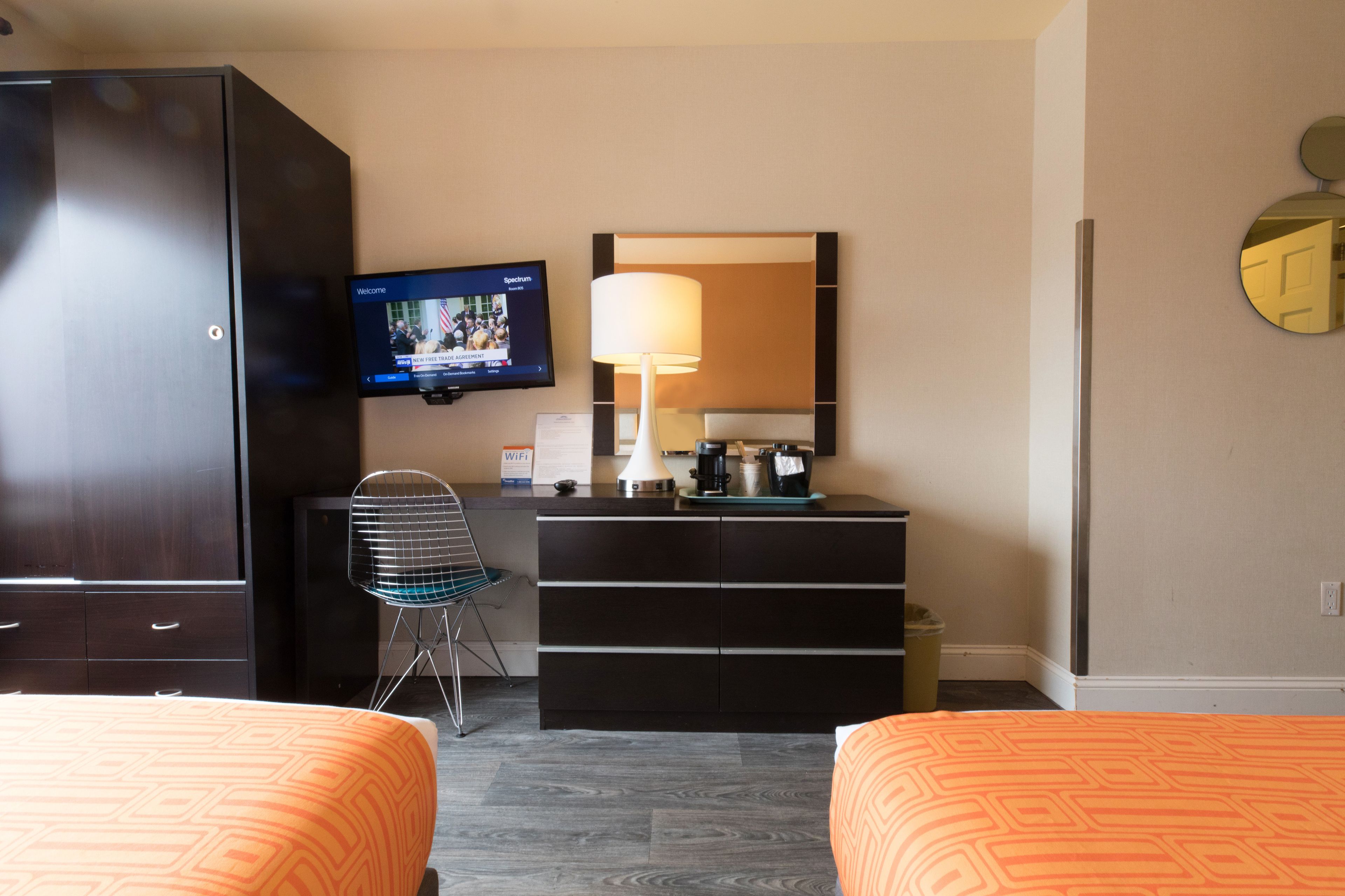 Habitación de hotel con dos camas, televisión, escritorio con lámpara y espejo.