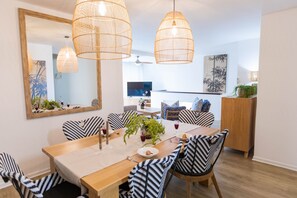 A dining area with a wooden table, striped chairs, and hanging wicker lamps. - First Group Cape Gordonia (Cape Town)