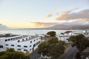A coastal cityscape with white buildings, a marina, and a mountain in the background. - First Group Cape Gordonia (Cape Town)