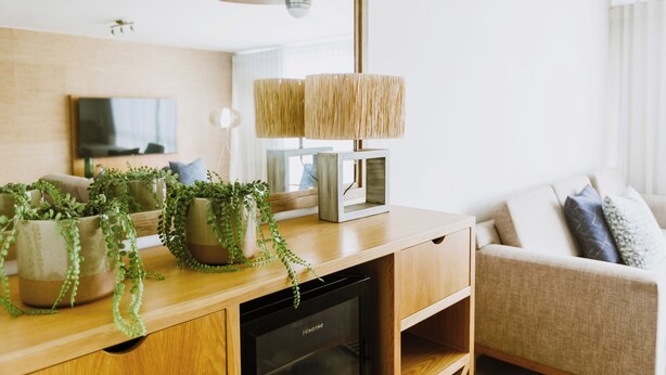 Uma sala de estar moderna com uma mesa de centro de madeira, plantas em vasos, uma televisão e um ventilador de teto.
