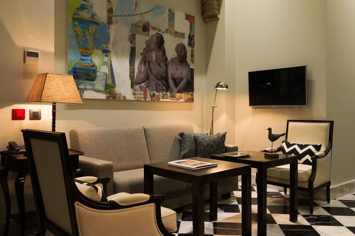Ein Wohnzimmer mit Sofa, Sesseln, Couchtisch, Lampe, Flachbildfernseher und einer Wand mit einem großen abstrakten Gemälde.