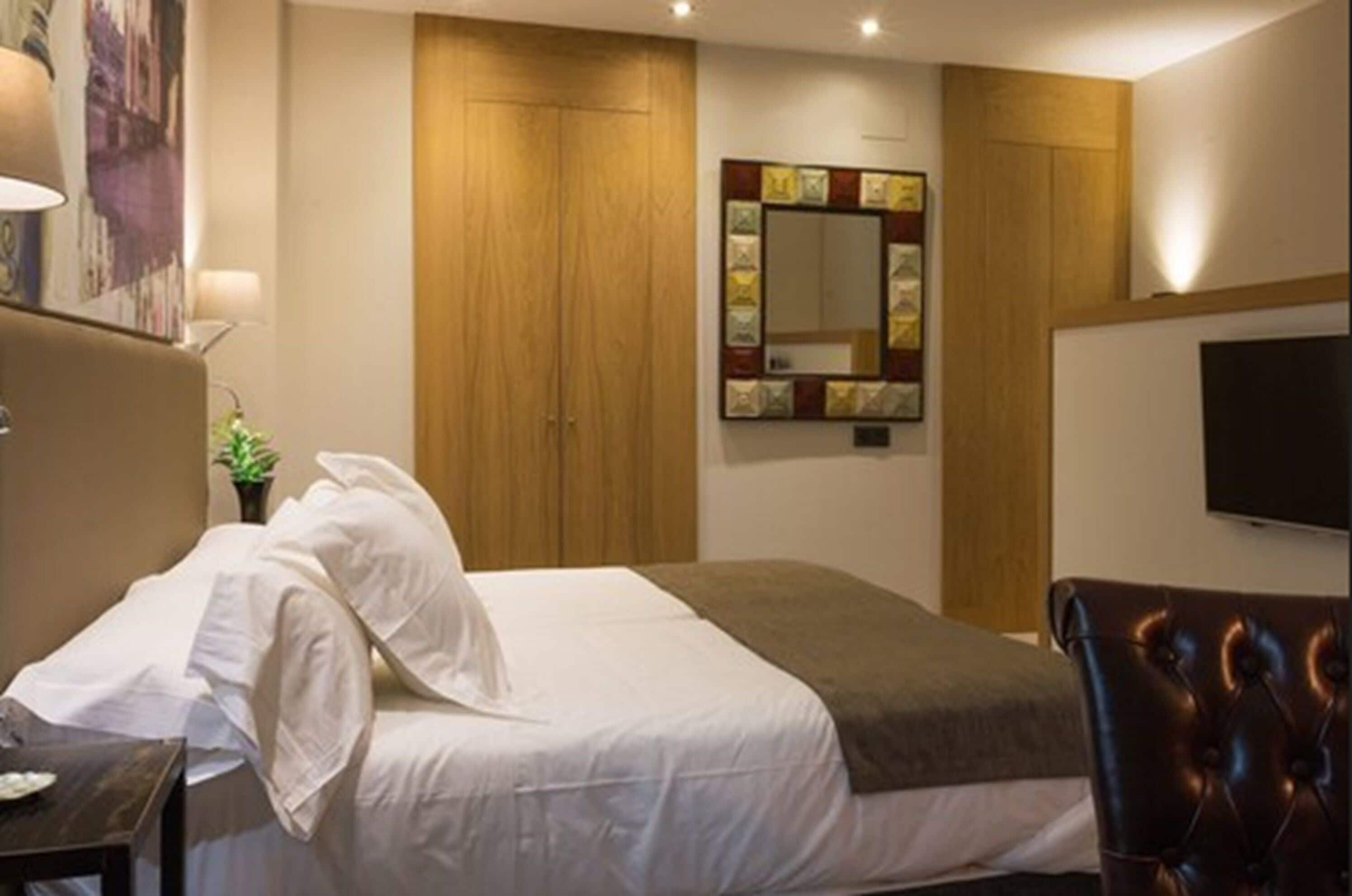 Ein Hotelzimmer mit Bett, Schreibtisch, Stuhl, Fernseher und Kleiderschrank.