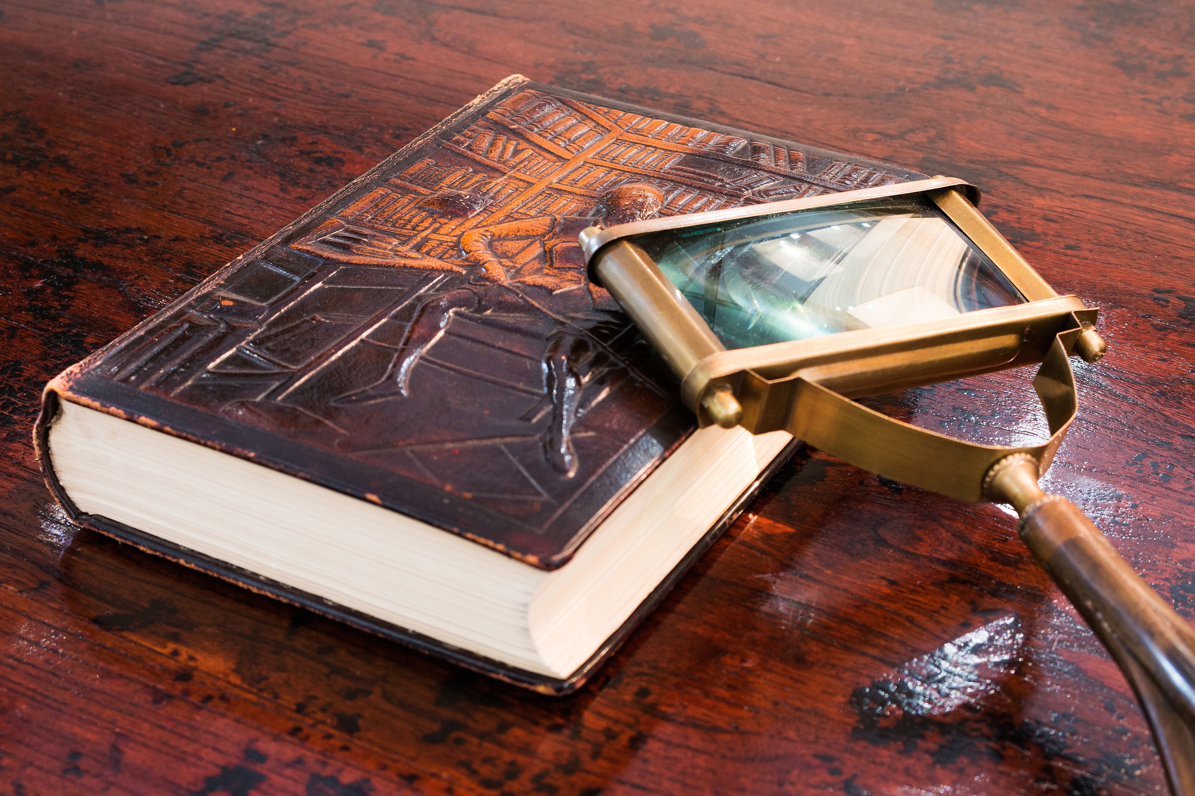 A book with a magnifying glass on a wooden surface.