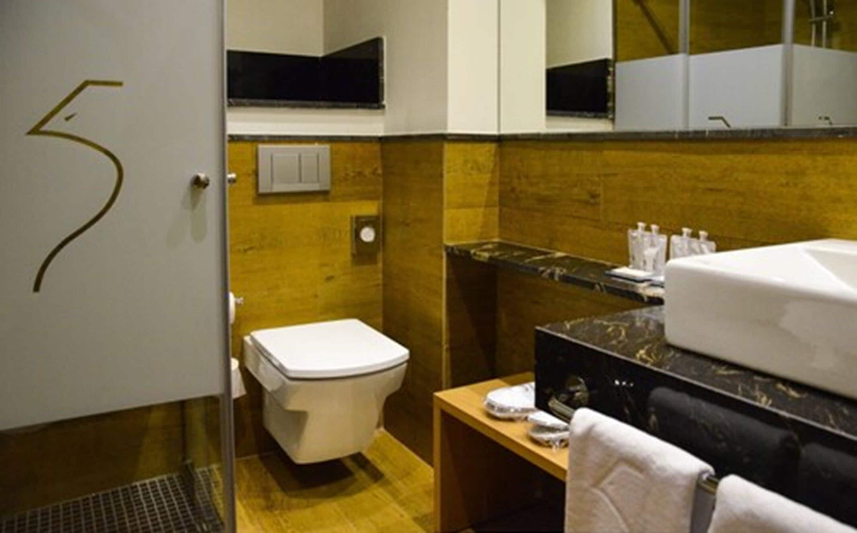 A bathroom with a toilet, sink, and mirror.