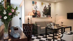 A living room with a checkered floor, a sofa, a coffee table, and a decorative vase with flowers. - Aguilas5 SevillaSuites (Seville)