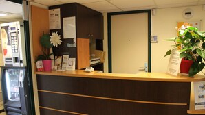 A reception desk with a vending machine, a potted plant, and a door. - Premiere Classe Saint Ouen L'Aumone (Saint-Ouen-l'Aumone)