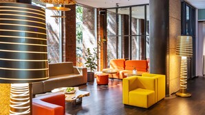 Un espacio lounge moderno con sofás de cuero, una mesa de centro de madera y dos lámparas de pie.