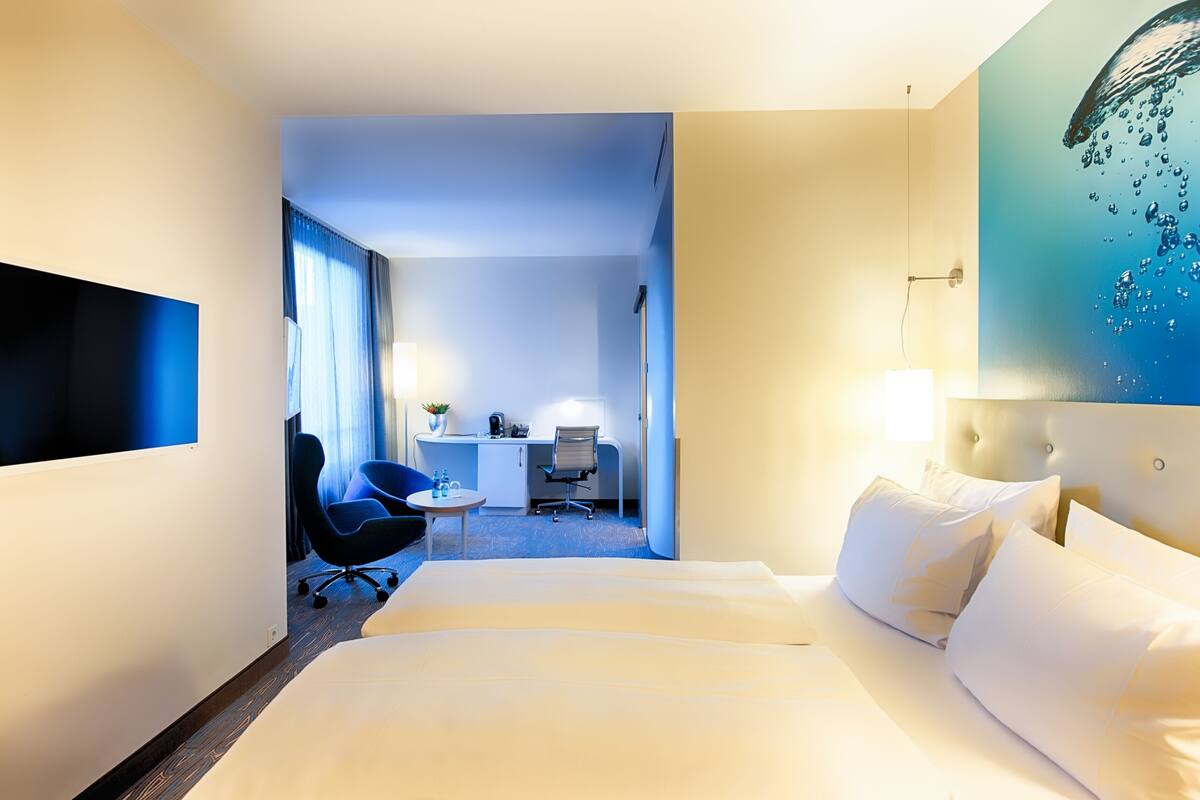 Une chambre d’hôtel avec un lit, un bureau, une chaise et un téléviseur.