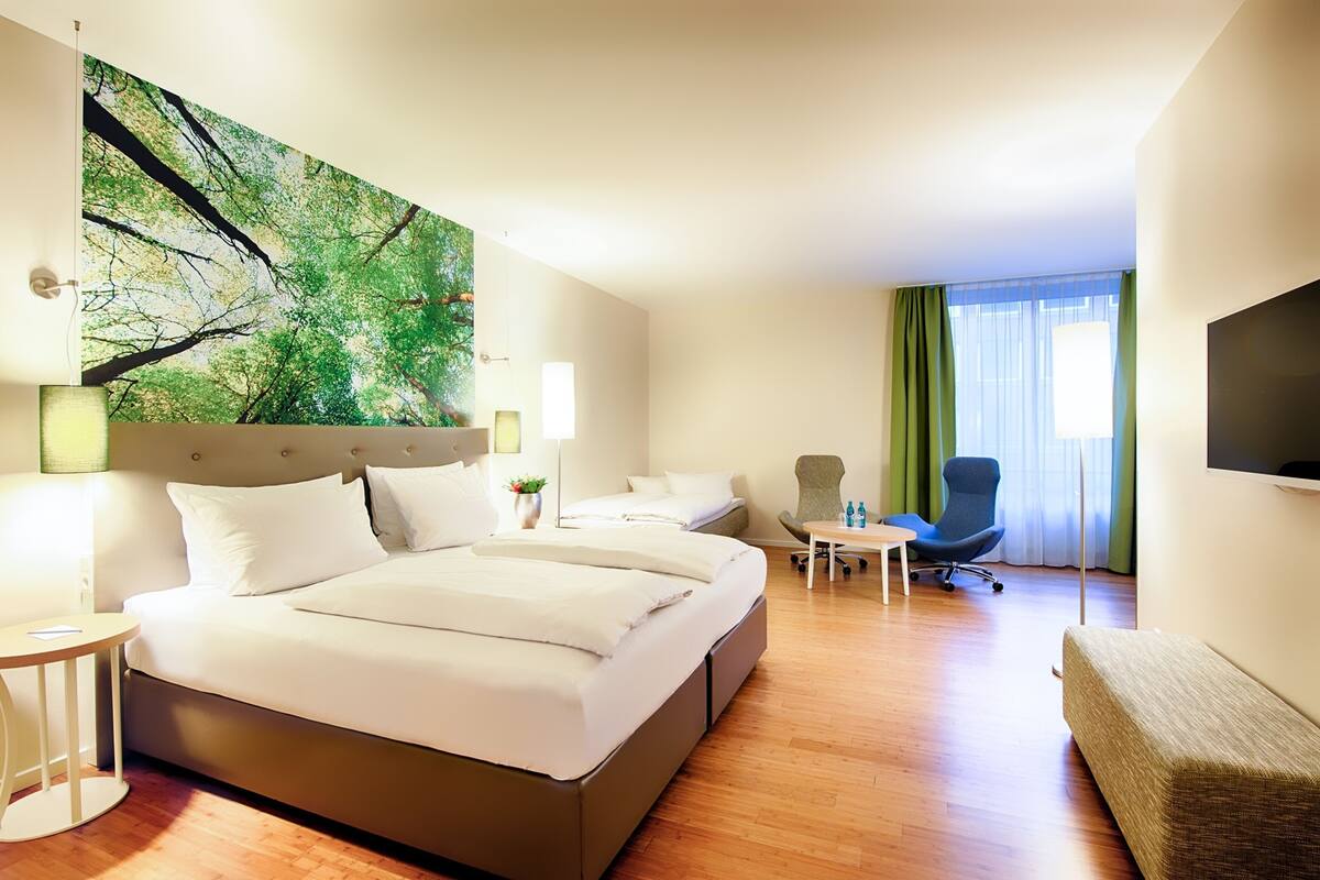 Une chambre d’hôtel avec un grand lit, un bureau, une chaise, une télévision et un tableau au mur.