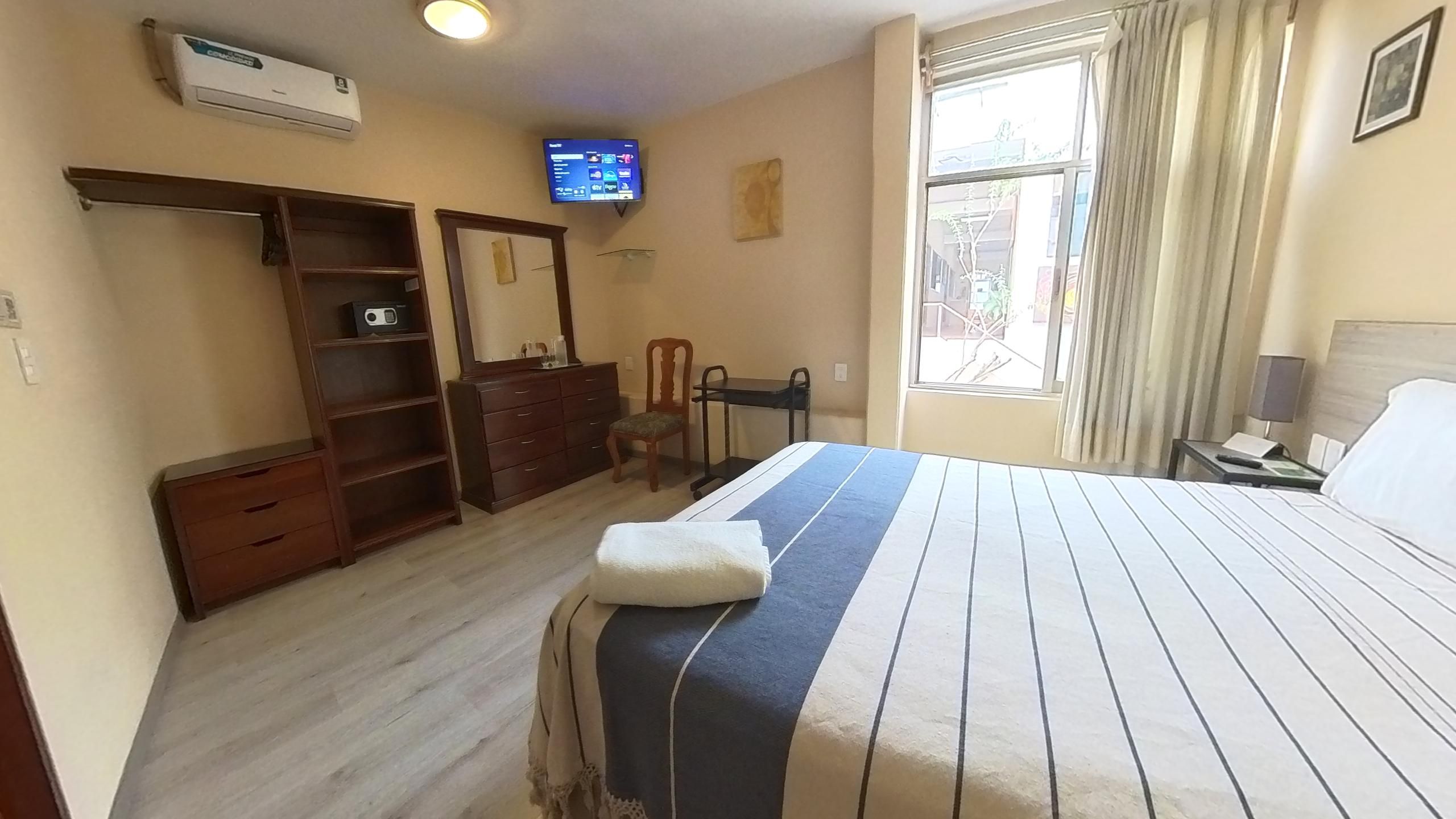 A hotel room with a bed, a television, a desk, and a wardrobe.
