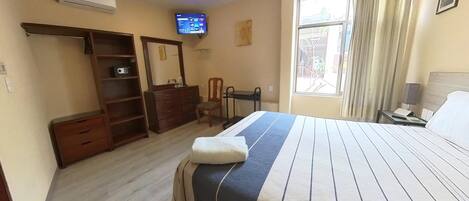 A hotel room with a bed, a television, a desk, and a wardrobe.