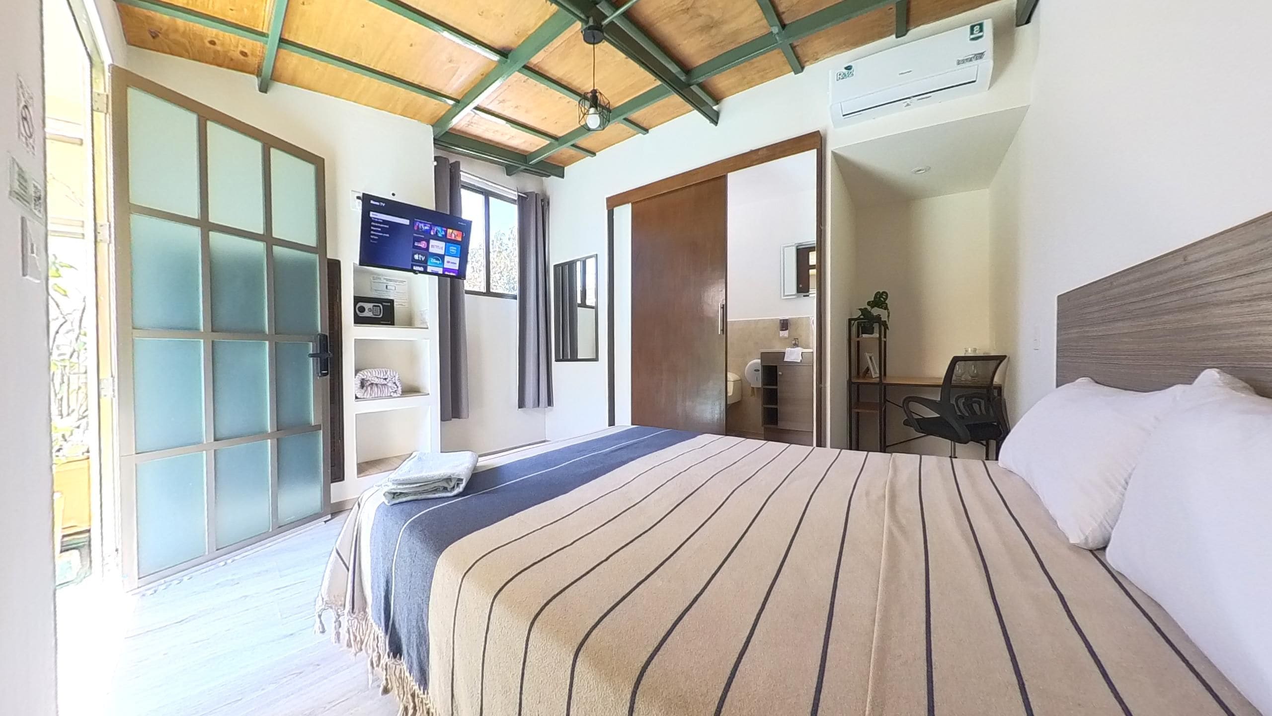 A hotel room with a bed, a TV, a desk, and a bathroom.