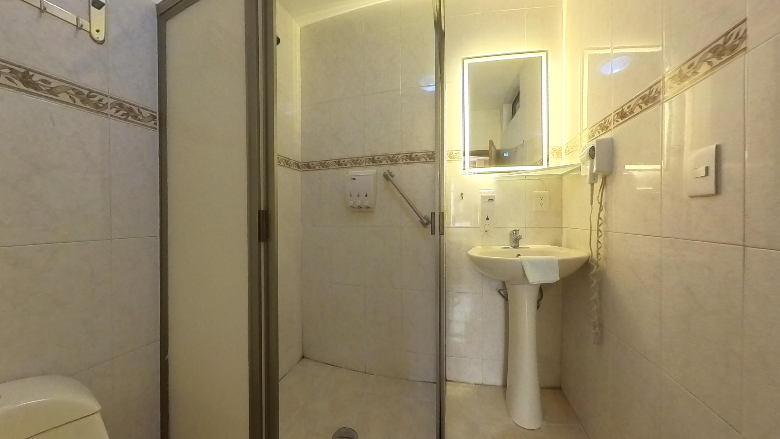 Une salle de bain avec une douche à parois de verre, un lavabo sur colonne et un miroir au-dessus.