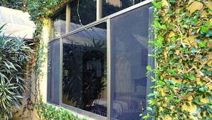 A window with a view of indoor plants and furniture, surrounded by climbing plants. - Hotel Don Nino (Oaxaca)