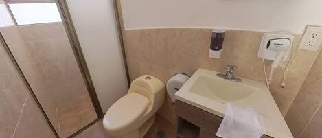 A bathroom with a toilet, sink, and shower area.