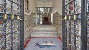 A staircase with ornate railings and a patterned carpet leading to a door.