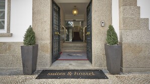 A hotel entrance with a sign reading "Suites & Hostel" and a number "119" on the wall.