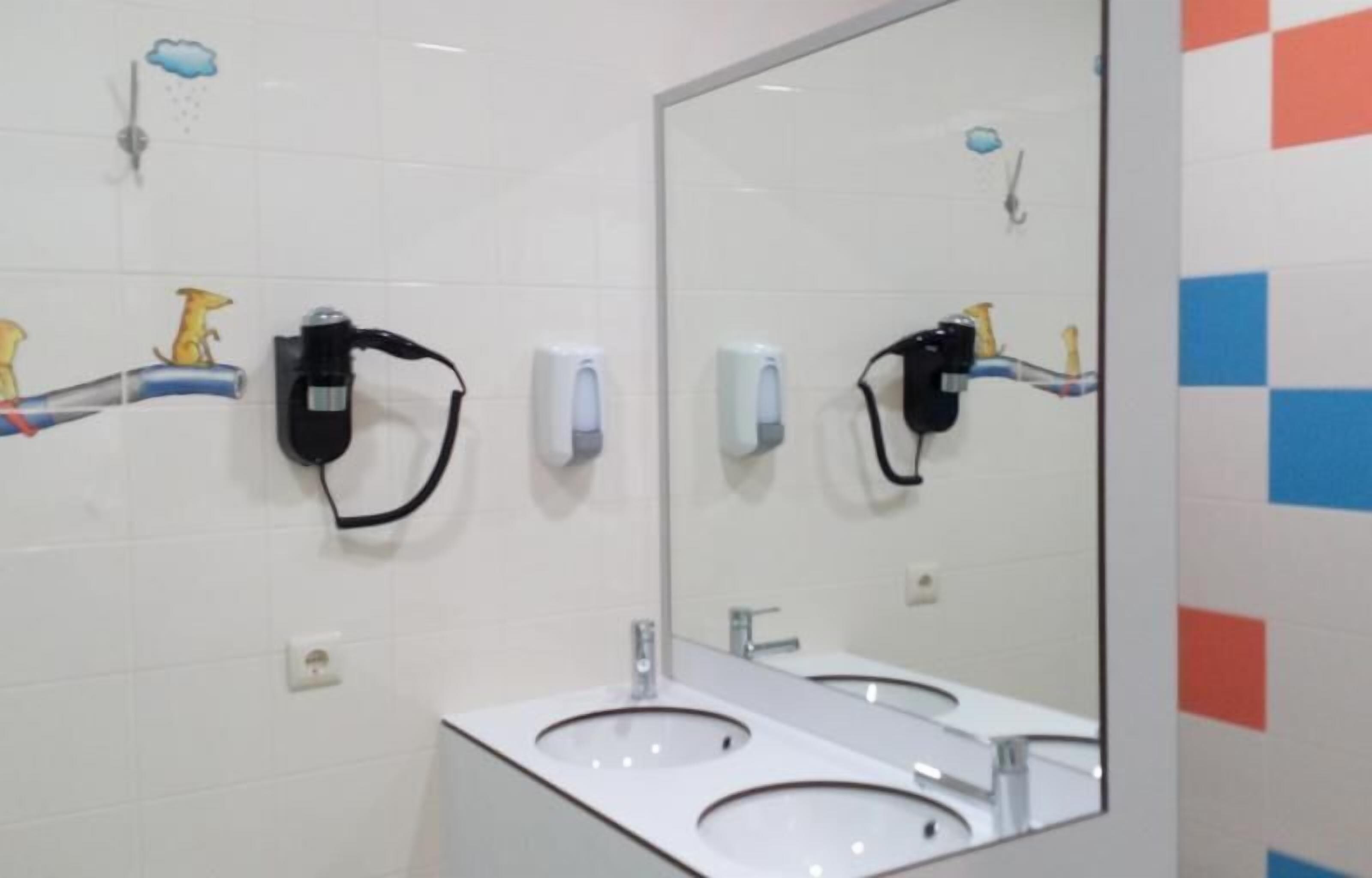 A restroom with two sinks, hand dryers, and soap dispensers.