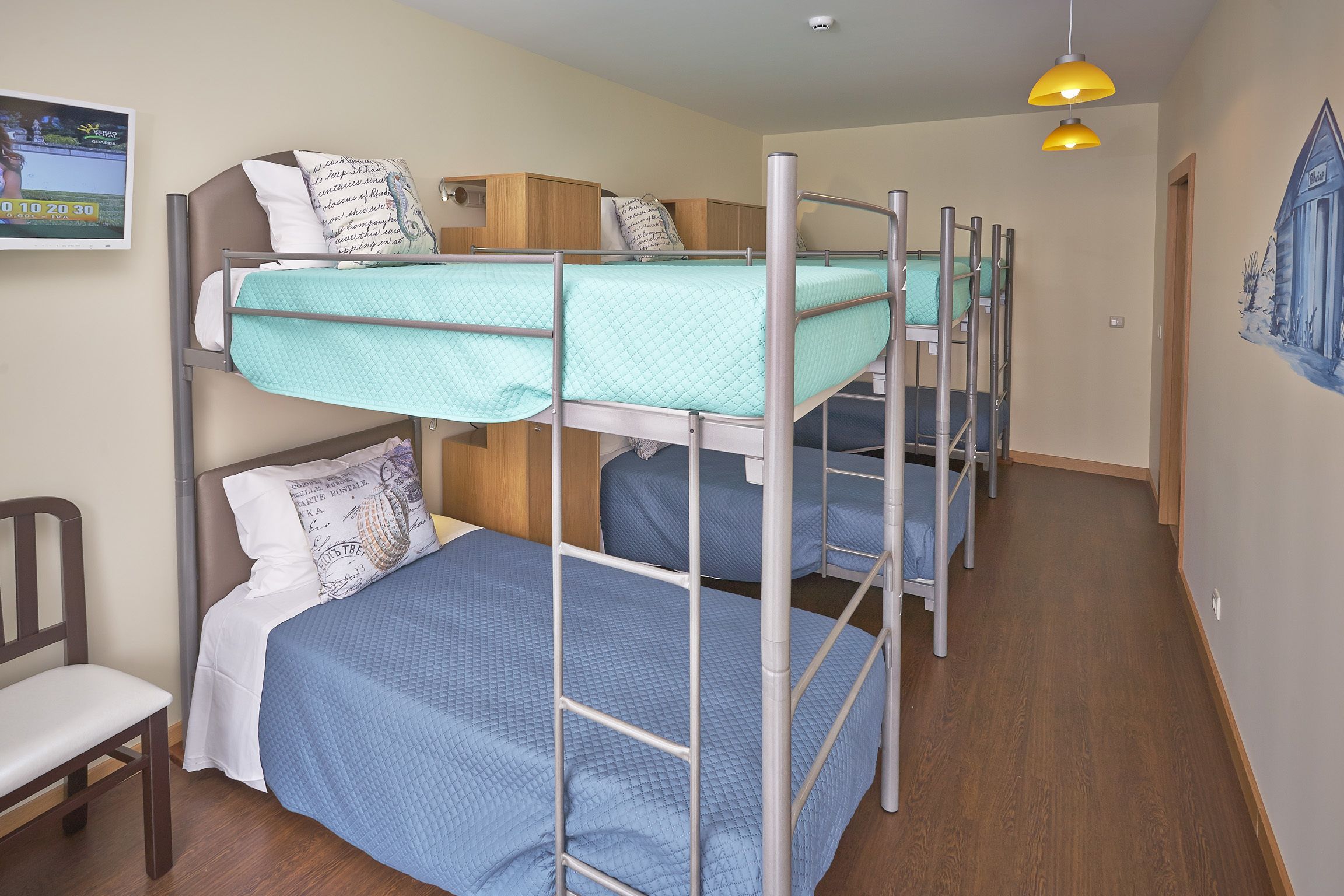 Um quarto em dormitório com beliches, uma escrivaninha e uma cadeira.