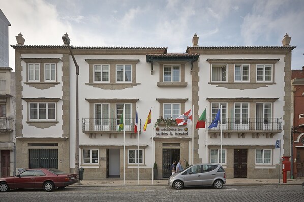 Um edifício com uma placa que diz "Welcome in Suites & Hostel" e várias bandeiras.