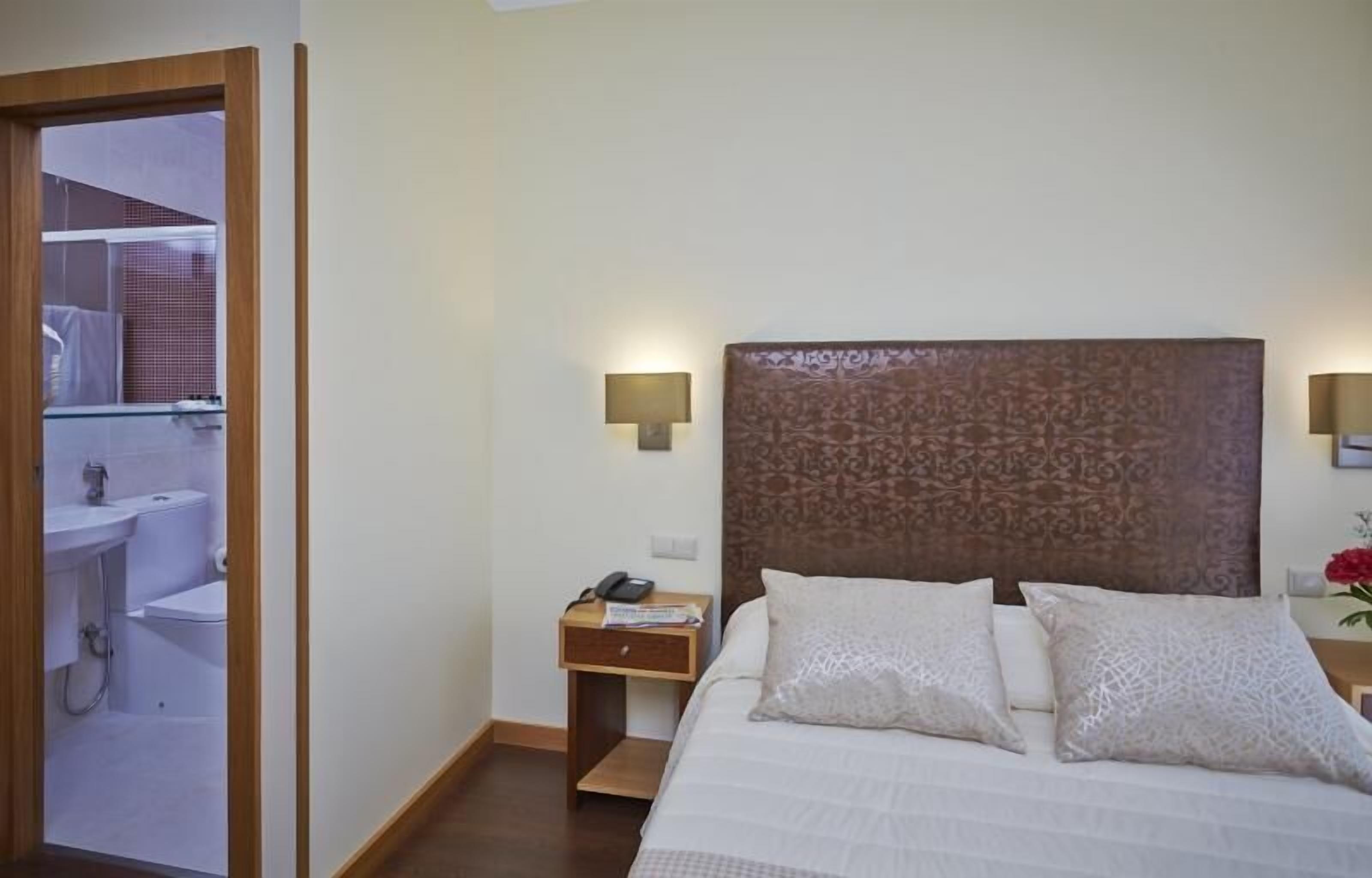 Et hotelværelse med en seng, et natbord, en lampe og udsigt til badeværelset.