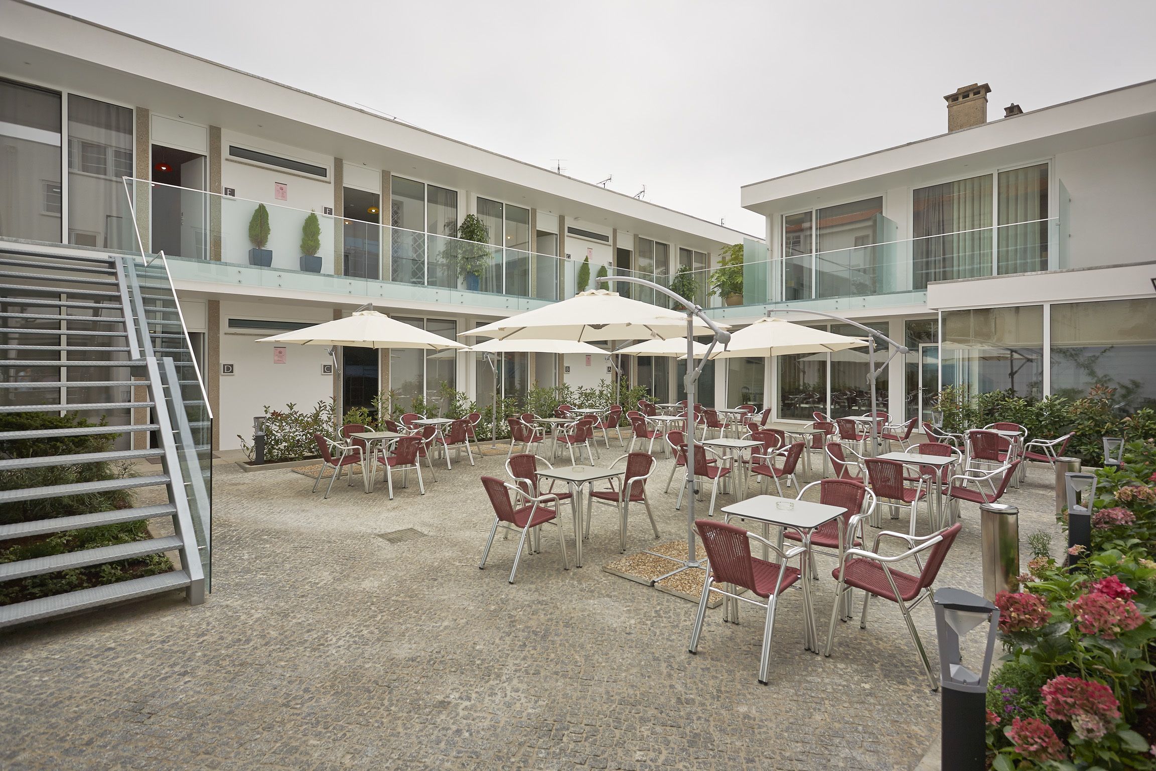 A modern building with outdoor seating, a staircase, and potted plants.