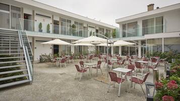 A modern building with outdoor seating, a staircase, and potted plants.