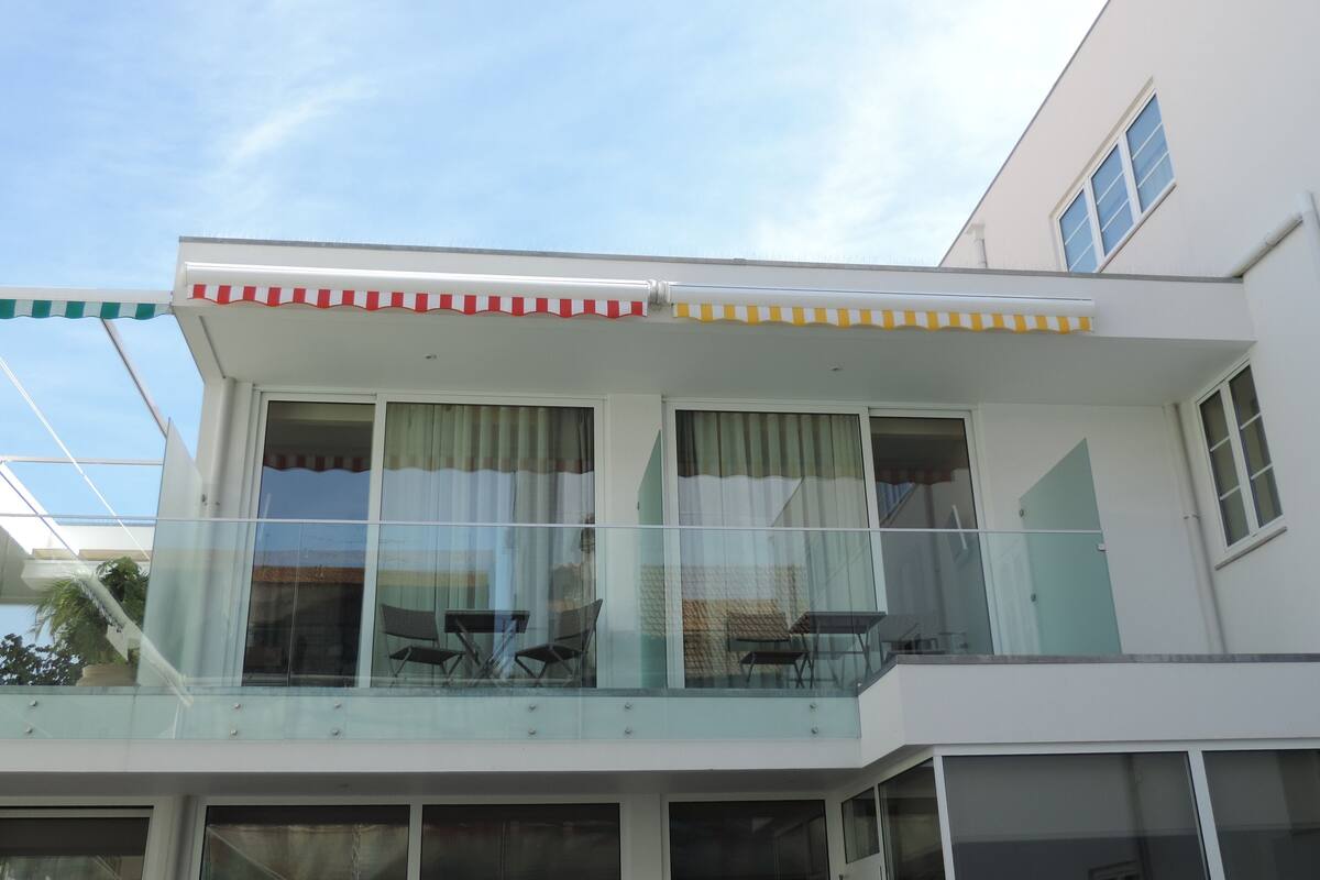 A modern building with a balcony, large windows, and a flat roof.