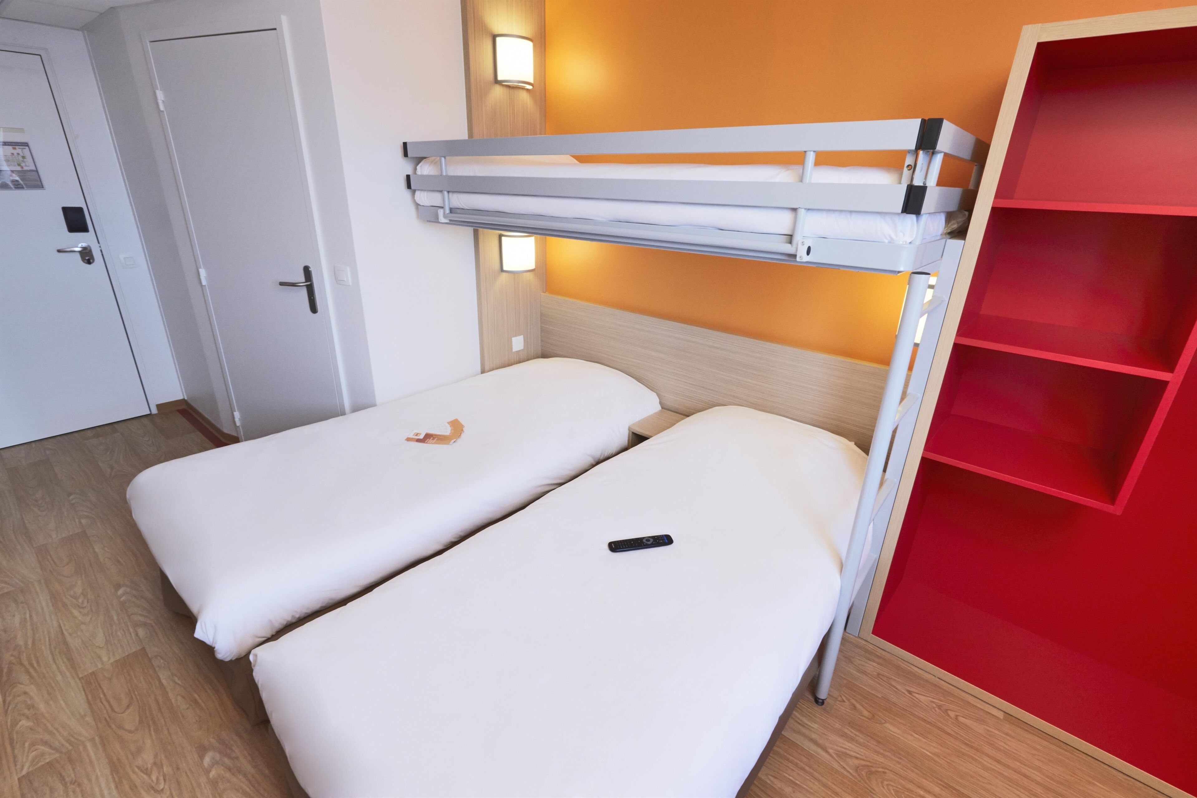A bunk bed with a red storage unit beside it.