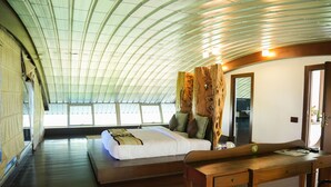 A spacious room with a large bed, a wooden desk, and a curved ceiling. - Regenta Beach House Resort, Goa (Colva)