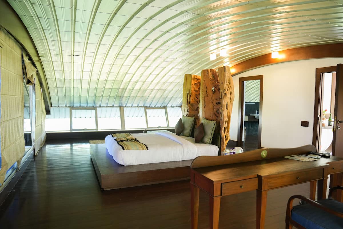 A spacious room with a large bed, a wooden desk, and a curved ceiling.