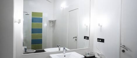 A modern bathroom with a large mirror, white sink, and a shower area.