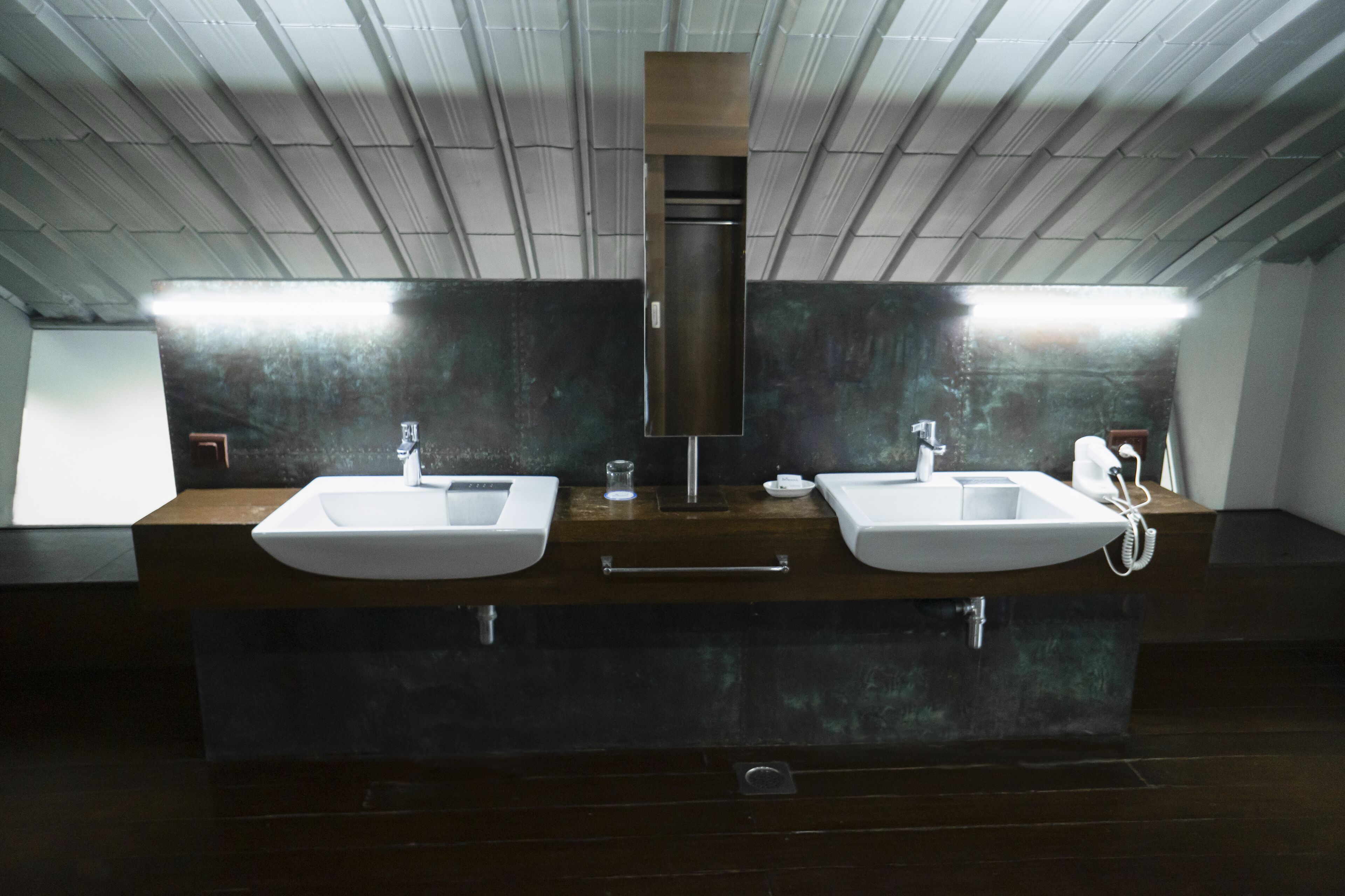 A modern bathroom with two sinks, a mirror, and a ventilation hood.