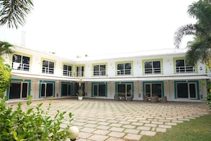 A two-story building with a courtyard, featuring multiple doors and windows, and outdoor seating areas.
