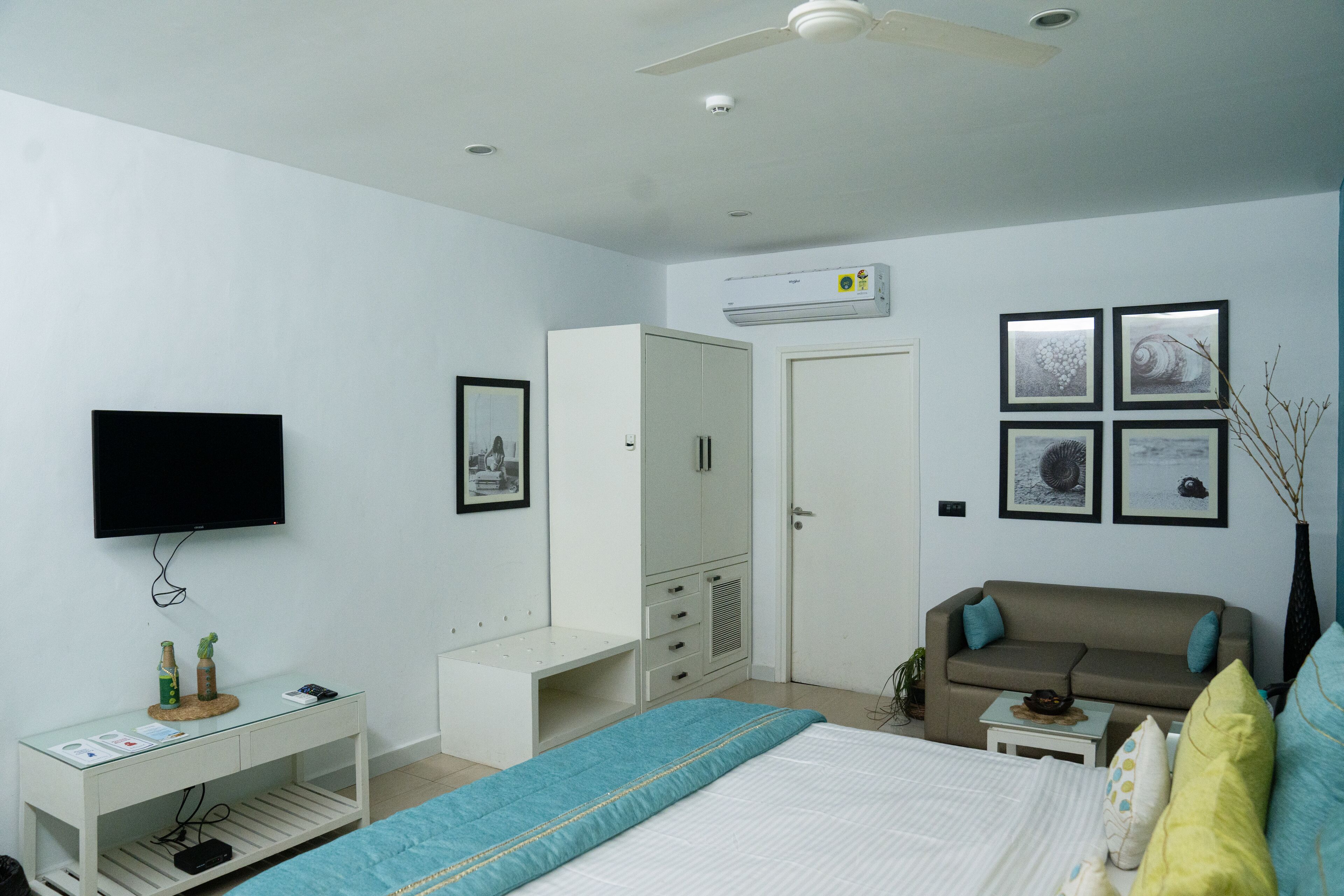 A bedroom with a bed, a TV, a wardrobe, a small table, and a sofa.