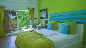 Un dormitorio con una cama grande, vistas al verdor exterior y una pared de color verde brillante.